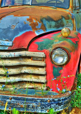 Detail of the front end of an old rusted abandoned vintage truck.  There are wild flowers growing in front of it. Stock Photo - Budget Royalty-Free & Subscription, Code: 400-05738409