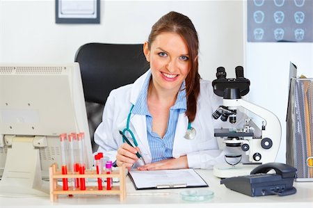 simsearch:400-04925813,k - Smiling female medical doctor working with documents at office Stock Photo - Budget Royalty-Free & Subscription, Code: 400-05739357