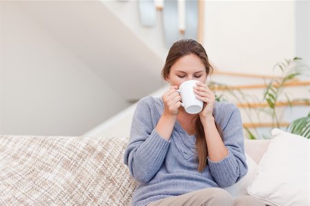 Woman having a cup of coffee while sitting on her sofa Stock Photo - Budget Royalty-Free & Subscription, Code: 400-05739903
