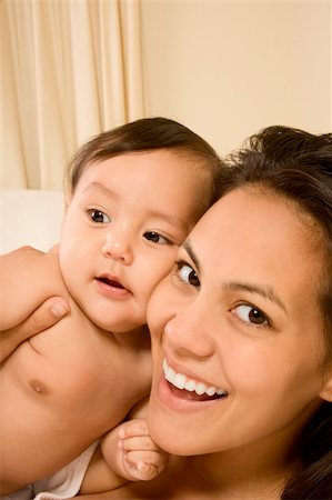 simsearch:400-04530129,k - Mom and son on bed and mother embracing the infant baby, who looks aside of camera with serious facial expression Stock Photo - Budget Royalty-Free & Subscription, Code: 400-05730390