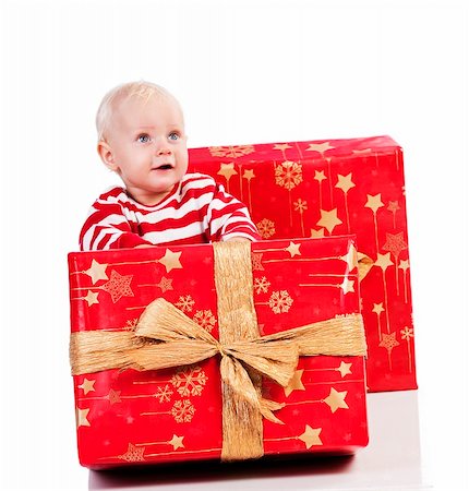 sweet and funny shot of a baby boy in red t-shirt playing with two big christmas gift box. baby is sitting behind the small gift box Stock Photo - Budget Royalty-Free & Subscription, Code: 400-05730561