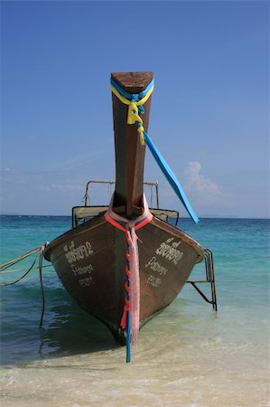 simsearch:400-05097850,k - Typical longtail boat with colorful ribbons seen from the front at Bamboo Island beach. Purple sea and blue sky in background. Stockbilder - Microstock & Abonnement, Bildnummer: 400-05730769