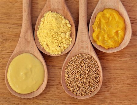 dijon - Mustard selection of dijon, powder, seeds and english in wooden spoons over oak background. Foto de stock - Royalty-Free Super Valor e Assinatura, Número: 400-05730975