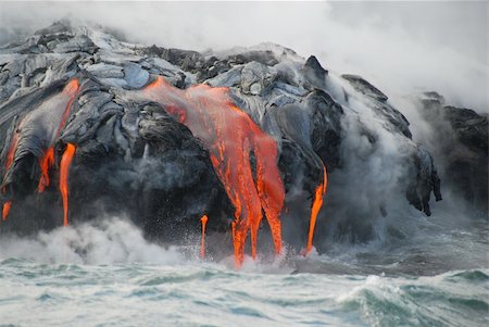 simsearch:400-05114623,k - Red hot lava from Kilauea Volcano on the Big Island of Hawaii flows through lava tubes and pours like rivers into the ocean, bringing up clouds of steam and toxic gas, creating acres of lava rock and adding new land to the island. Fotografie stock - Microstock e Abbonamento, Codice: 400-05732741