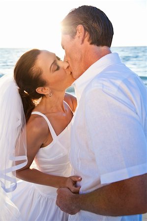 A married couple, bride and groom, kissing at sunset on a beautiful tropical beach Foto de stock - Super Valor sin royalties y Suscripción, Código: 400-05745198
