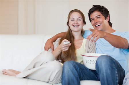 simsearch:400-05748052,k - Laughing couple watching television while eating popcorn in their living room Foto de stock - Super Valor sin royalties y Suscripción, Código: 400-05746674