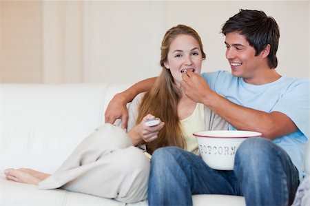 simsearch:400-05748052,k - Happy couple watching television while eating popcorn in their living room Foto de stock - Super Valor sin royalties y Suscripción, Código: 400-05746672