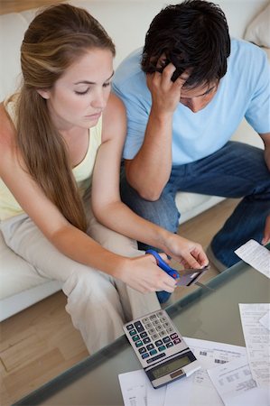 Portrait of a couple cutting their credit card in their living room Stock Photo - Budget Royalty-Free & Subscription, Code: 400-05746767