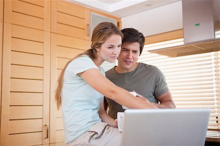 download - Young couple having tea while using a laptop in their kitchen Stock Photo - Budget Royalty-Free & Subscription, Code: 400-05746844
