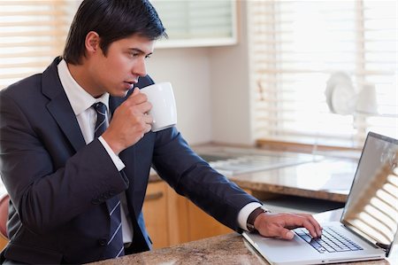 simsearch:400-05737647,k - Man working with a notebook while drinking tea in his kitchen Stock Photo - Budget Royalty-Free & Subscription, Code: 400-05746911