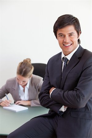 simsearch:400-04287075,k - Portrait of an office worker posing while his colleague is working in an office Fotografie stock - Microstock e Abbonamento, Codice: 400-05746963