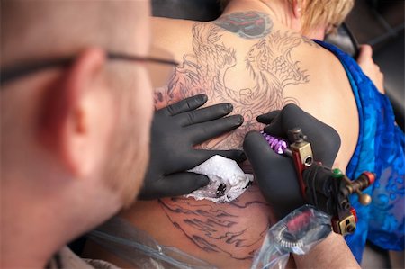 simsearch:400-04343139,k - Male tattoo artist draws a design on back of client Photographie de stock - Aubaine LD & Abonnement, Code: 400-05747818