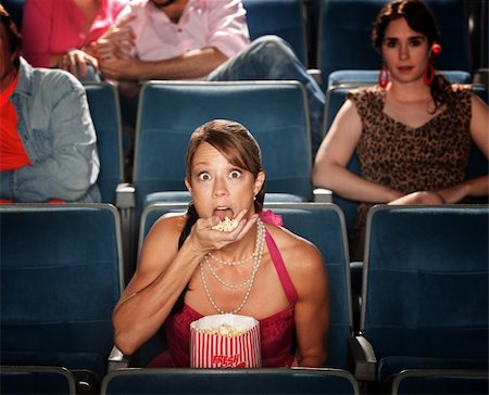 simsearch:400-06138368,k - Shocked Caucasian woman eats popcorn in theater Fotografie stock - Microstock e Abbonamento, Codice: 400-05747856