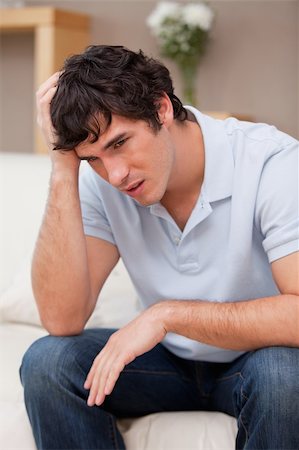 simsearch:400-06875322,k - Despaired young man sitting on the sofa Fotografie stock - Microstock e Abbonamento, Codice: 400-05747990