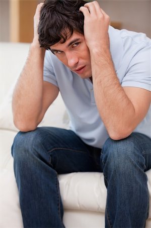 simsearch:400-06875322,k - Frustrated young man sitting on the sofa Fotografie stock - Microstock e Abbonamento, Codice: 400-05747993