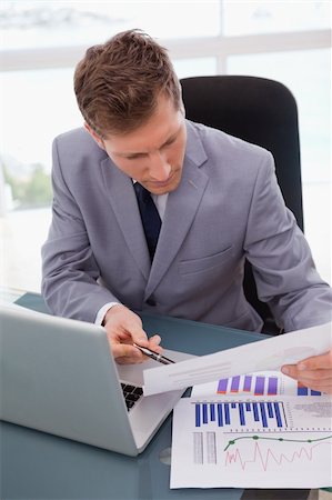 simsearch:400-05748158,k - Businessman at his desk looking at statistics Stock Photo - Budget Royalty-Free & Subscription, Code: 400-05748280