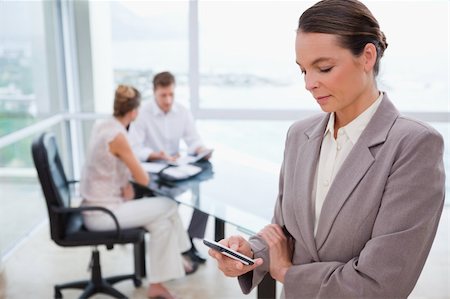 Standing real estate agent with cellphone and sitting clients behind her Stock Photo - Budget Royalty-Free & Subscription, Code: 400-05748335