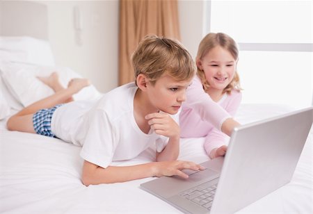 simsearch:400-05748382,k - Siblings using a notebook in a bedroom Fotografie stock - Microstock e Abbonamento, Codice: 400-05748379