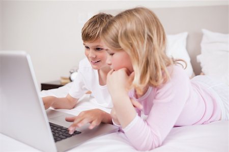 simsearch:400-05748382,k - Smiling children using a laptop in a bedroom Fotografie stock - Microstock e Abbonamento, Codice: 400-05748385