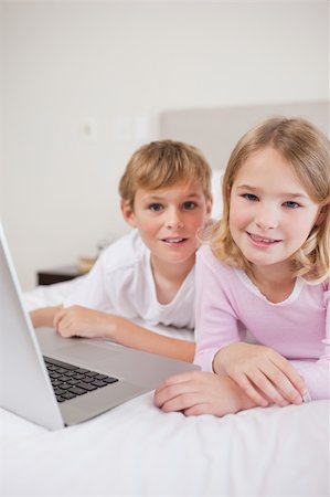 simsearch:400-05748382,k - Portrait of cute children using a laptop in a bedroom Fotografie stock - Microstock e Abbonamento, Codice: 400-05748387
