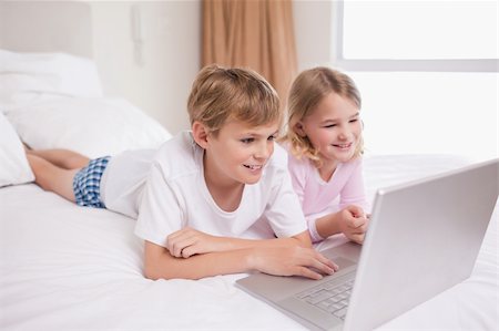 simsearch:400-05748382,k - Smiling children using a notebook in a bedroom Fotografie stock - Microstock e Abbonamento, Codice: 400-05748383