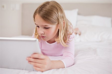 simsearch:400-05748382,k - Little girl using a tablet computer in a bedroom Fotografie stock - Microstock e Abbonamento, Codice: 400-05748396