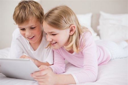 simsearch:400-04157521,k - Smiling siblings using a tablet computer in a bedroom Stock Photo - Budget Royalty-Free & Subscription, Code: 400-05748392