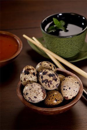 drink coaster - Delicate, beautiful Quail Eggs in a wood bowl.  A green cast iron tea cup is to the side along with chopsticks and a bowl of red dipping sauce.  Shallow depth of field. Stock Photo - Budget Royalty-Free & Subscription, Code: 400-05748495