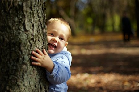 beautiful laughing little boy  hiding and peeking from behind a tree Stock Photo - Budget Royalty-Free & Subscription, Code: 400-05748500