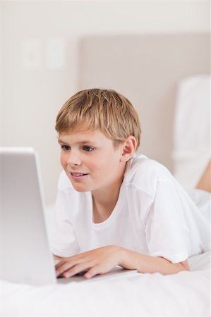 simsearch:400-05748382,k - Portrait of a cute boy using a laptop in a bedroom Fotografie stock - Microstock e Abbonamento, Codice: 400-05749386