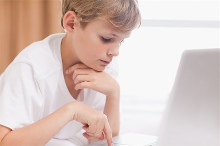 simsearch:400-05748382,k - Young boy using a laptop in a bedroom Fotografie stock - Microstock e Abbonamento, Codice: 400-05749389