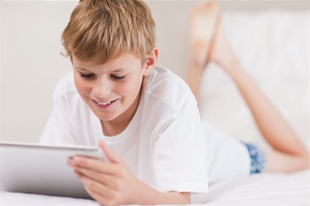 simsearch:400-05748382,k - Young boy using a tablet computer in a bedroom Fotografie stock - Microstock e Abbonamento, Codice: 400-05749382