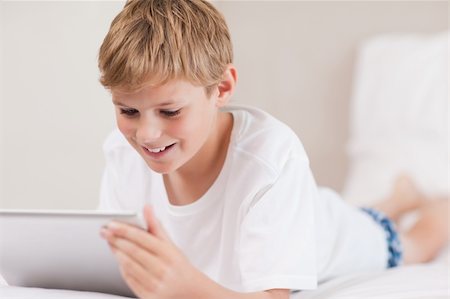 simsearch:400-05748382,k - Smiling boy using a tablet computer in a bedroom Fotografie stock - Microstock e Abbonamento, Codice: 400-05749383