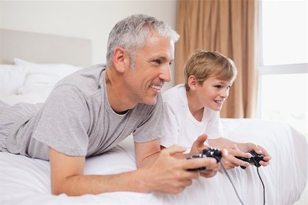 simsearch:400-04200290,k - Happy father and his son playing video games in a bedroom Stock Photo - Budget Royalty-Free & Subscription, Code: 400-05749398