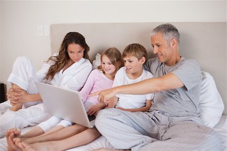 simsearch:400-05748382,k - Family using a laptop in a bedroom Fotografie stock - Microstock e Abbonamento, Codice: 400-05749418