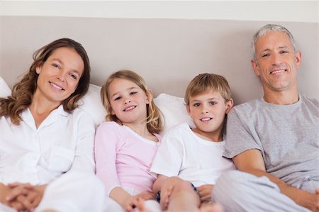 Family lying on a bed in while looking at the camera Stock Photo - Budget Royalty-Free & Subscription, Code: 400-05749411