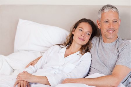 simsearch:400-05749447,k - Happy couple lying on a bed looking away from the camera Stock Photo - Budget Royalty-Free & Subscription, Code: 400-05749424