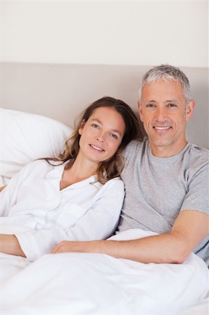 simsearch:400-05749442,k - Portrait of a couple lying on a bed while looking at the camera Photographie de stock - Aubaine LD & Abonnement, Code: 400-05749425