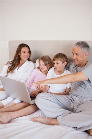 simsearch:400-05748382,k - Portrait of a family using a notebook in a bedroom Fotografie stock - Microstock e Abbonamento, Codice: 400-05749420