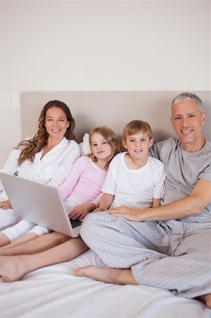 simsearch:400-05749479,k - Portrait of a family using a laptop in a bedroom Foto de stock - Royalty-Free Super Valor e Assinatura, Número: 400-05749421