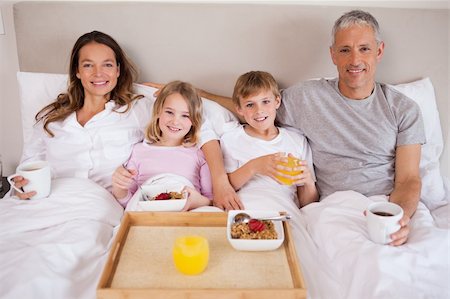 simsearch:400-05749624,k - Family having breakfast in a bedroom while looking at the camera Stock Photo - Budget Royalty-Free & Subscription, Code: 400-05749431