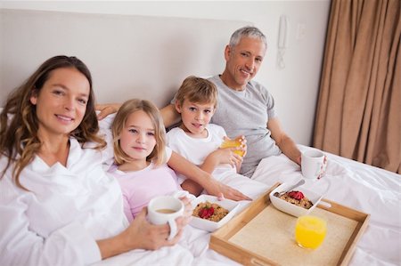 simsearch:400-05749624,k - Smiling family having breakfast in a bedroom while looking at the camera Stock Photo - Budget Royalty-Free & Subscription, Code: 400-05749432