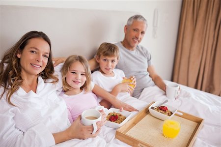 simsearch:400-05749624,k - Happy family having breakfast in a bedroom while looking at the camera Stock Photo - Budget Royalty-Free & Subscription, Code: 400-05749433