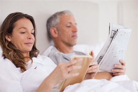 simsearch:400-05749447,k - Woman reading a book while her husband is reading the news in their bedroom Stock Photo - Budget Royalty-Free & Subscription, Code: 400-05749448