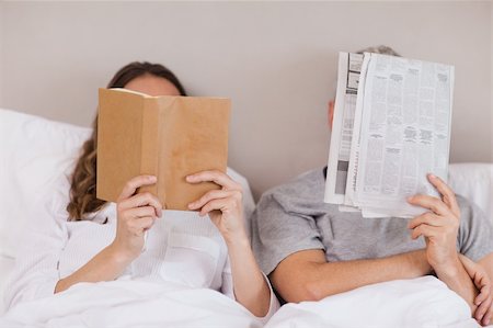 simsearch:400-05749442,k - Woman reading a book while her companion is reading a newspaper in their bedroom Photographie de stock - Aubaine LD & Abonnement, Code: 400-05749455