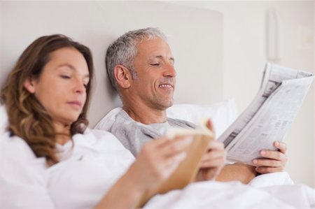 simsearch:400-05749447,k - Happy woman reading a book while her husband is reading a newspaper in their bedroom Stock Photo - Budget Royalty-Free & Subscription, Code: 400-05749450