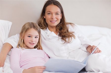 simsearch:400-05749644,k - Smiling girl reading a book with her mother in a bedroom Stock Photo - Budget Royalty-Free & Subscription, Code: 400-05749477