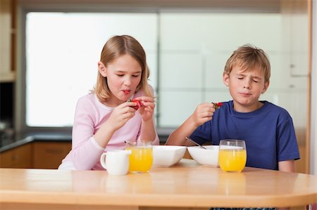 simsearch:400-04218582,k - Siblings eating strawberries for breakfast in a kitchen Photographie de stock - Aubaine LD & Abonnement, Code: 400-05749493