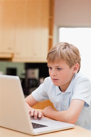 Portrait of a lovely boy using a laptop in a kitchen Stock Photo - Budget Royalty-Free & Subscription, Code: 400-05749519