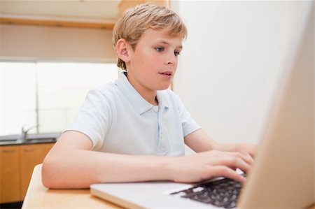 simsearch:400-04044137,k - Blond boy using a laptop in a kitchen Stock Photo - Budget Royalty-Free & Subscription, Code: 400-05749520